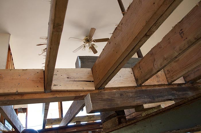 House lifted on steel I-beams over excavated foundation work