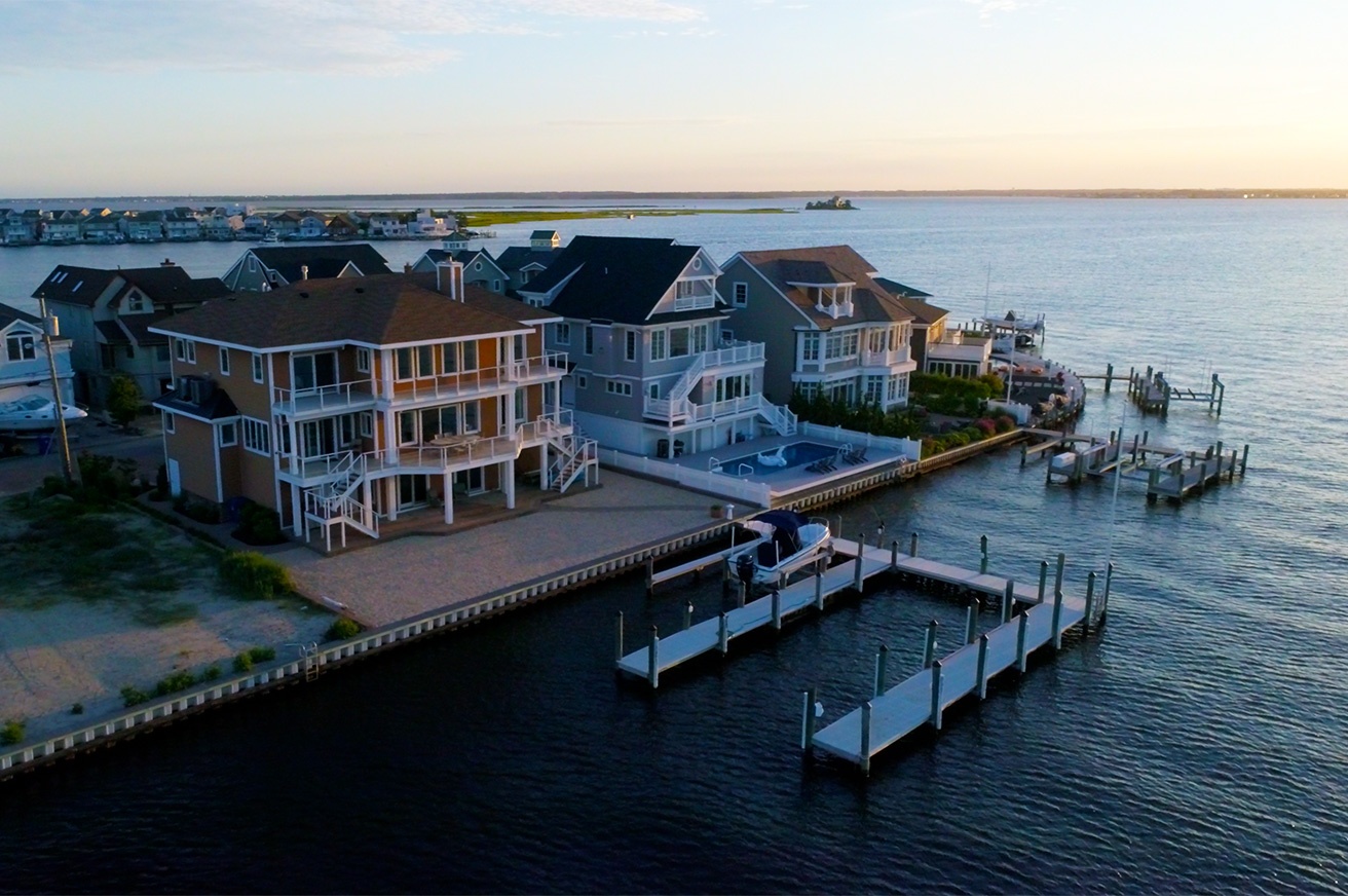 Aerial view of a JJC-built waterfront home with private dock at golden hour, Normandy Beach NJ